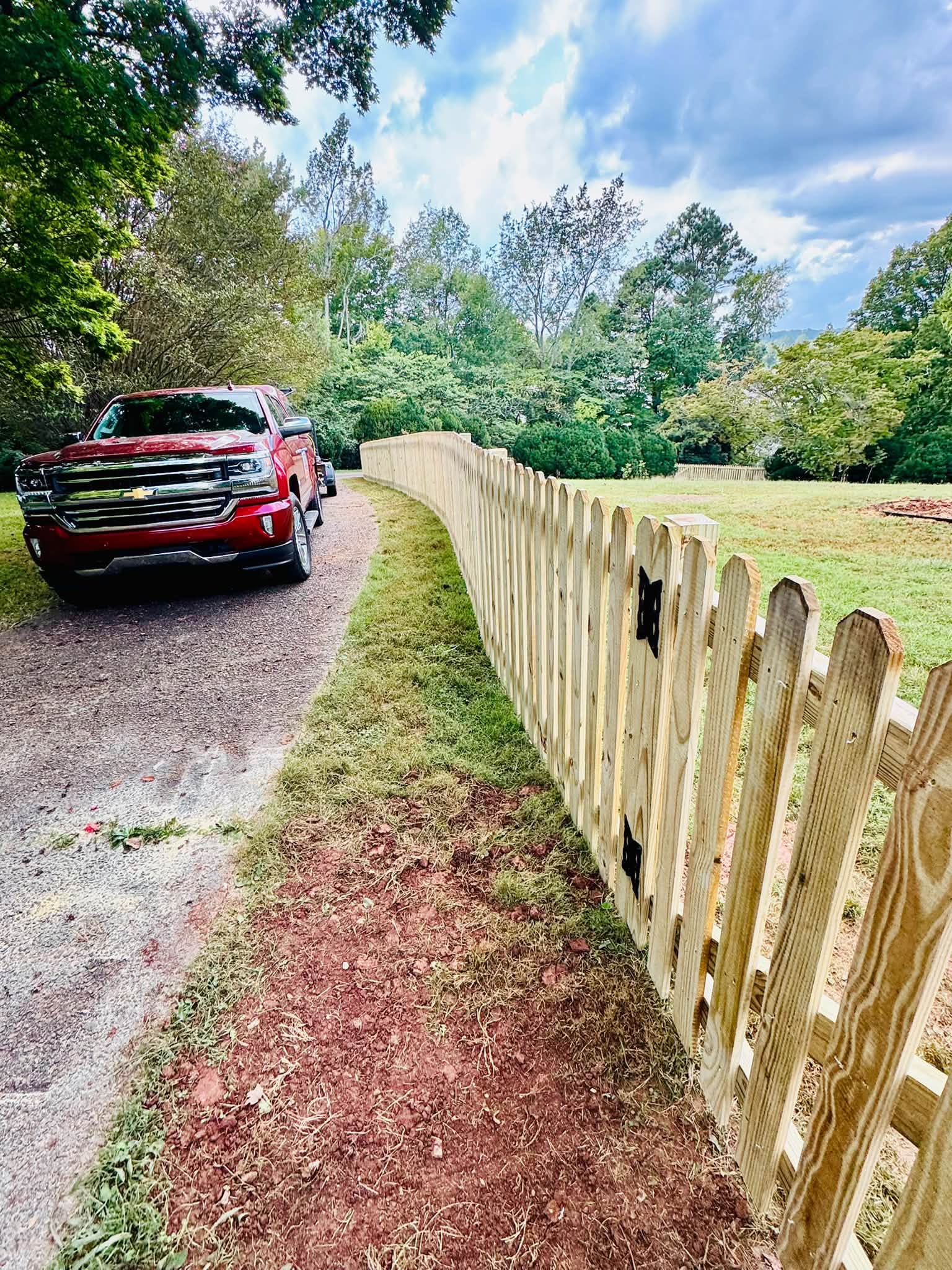 Long wood picket fence run along a country driveway in Athens, TN